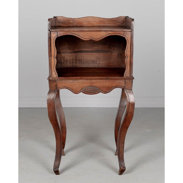 An early 20th century Louis XV Country French side table or nightstand made of solid walnut with an open niche and pierced...