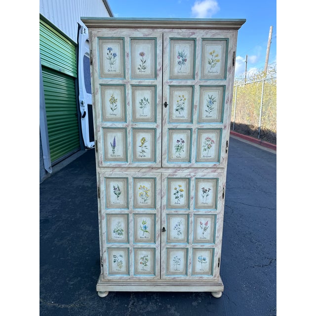 A striking late 20th-century cabinet featuring hand-painted botanical illustrations across the front doors, each...