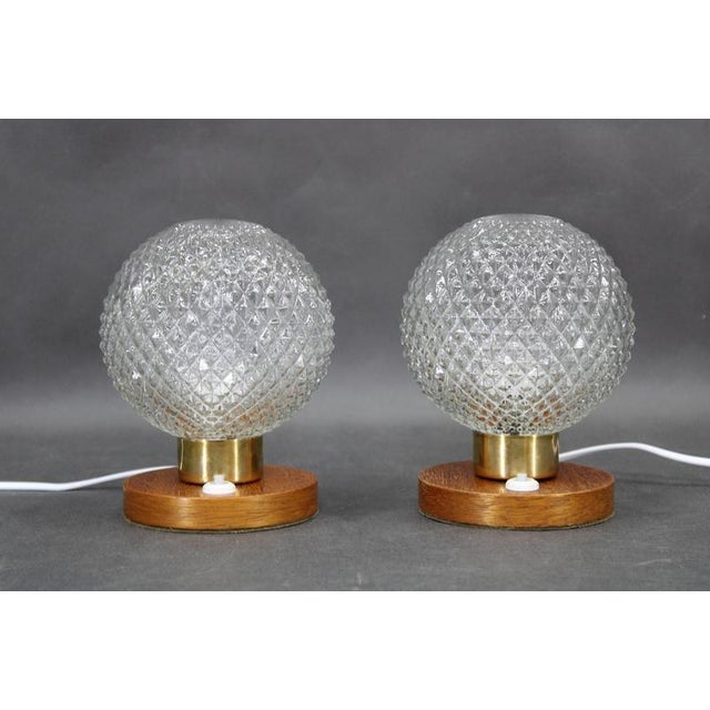 A refined pair of mid-century table lamps crafted in czechoslovakia in the 1970s, featuring solid wood bases, brass...