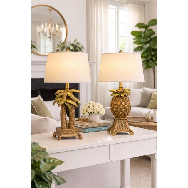 ✨ A sculptural and design-forward pair of Palm Beach Regency table lamps featuring complementary palm tree and pineapple...