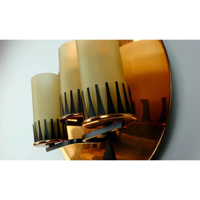 Beautiful wall lamp from the 50s to early 60s. It consists of a concave circular copper disk in front of a mount black-...