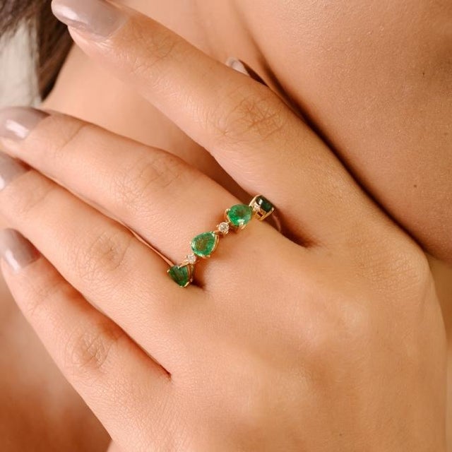 This elegant half eternity band showcases natural pear-cut emeralds totaling 1.27 carats, each measuring approximately 5x4...