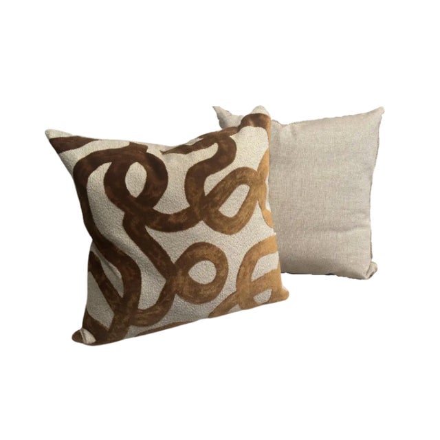 Decorative pillows featuring an organic abstract pattern in gold, on a soft neutral ground, creating a warm and...