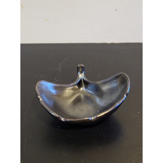 A small vintage handmade pottery trinket dish in the shape of a ginko leaf. Delicate realistic detailing and finished in a...