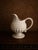 A charming vintage creamware pitcher standing 8" tall. This footed jug features layered embossed relief decoration...
