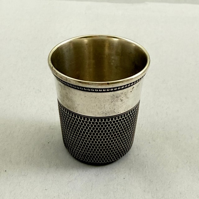 A sterling silver thimble jigger or whiskey shot cup bar tool for measuring out liquor when mixing cocktails. Showing the...