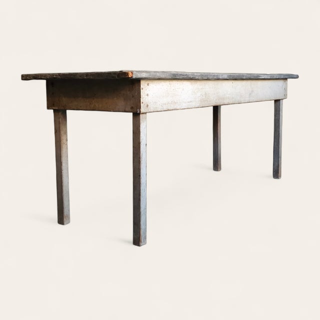 A long early 20th-century American primitive worktable featuring a beautifully weathered zinc top over a painted wooden...