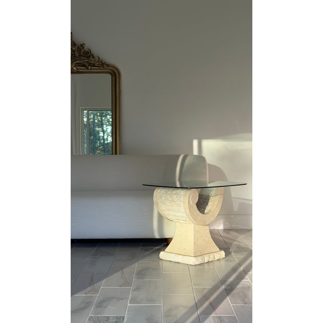 This glass top end table perfectly encapsulates the neoclassical style with its textured and carved stone base and its...
