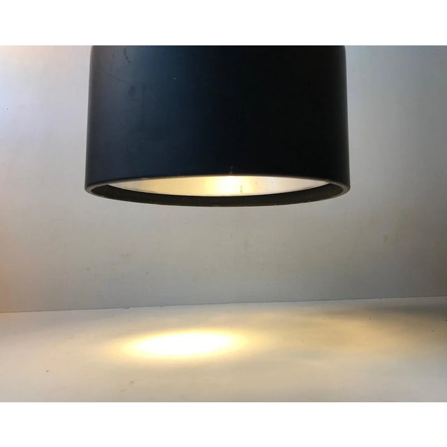 Adjustable wall lamp made from black powder coated steel and aluminium. It features a porcelain socket and reflective...
