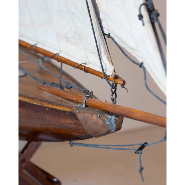 A finely crafted early 20th-century English planked pond yacht, showcasing a beautifully shaped hull with visible plank...