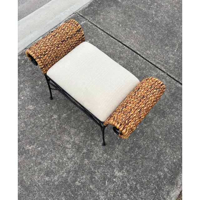 Wicker and Metal Bench with Light Colored Cushion . The Arms are in a Wrapped Rolled over Wicker.
