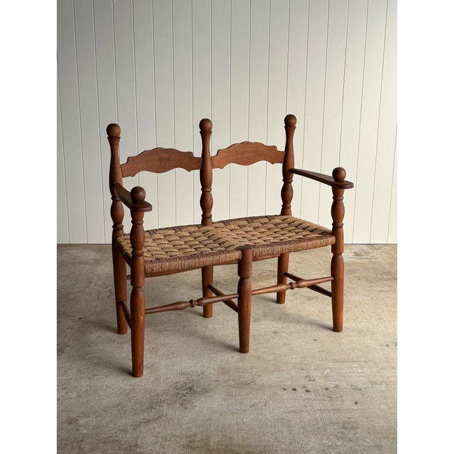 Vintage wooden bench with turned posts, ball finials, and carved shaped back rails. Hand-woven cord seat over a stretcher...