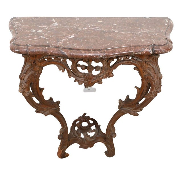 A rococo marble top carved wood wall mount console table. The hand-carved apron and supports showcase elaborate...