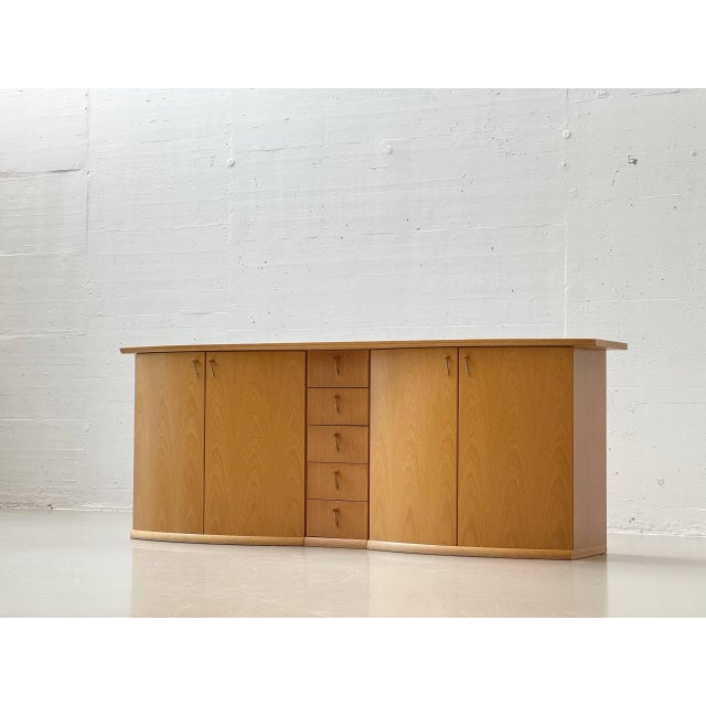 A generously proportioned, elegantly curved sideboard crafted from light beechwood with a beautiful grain and a clean,...