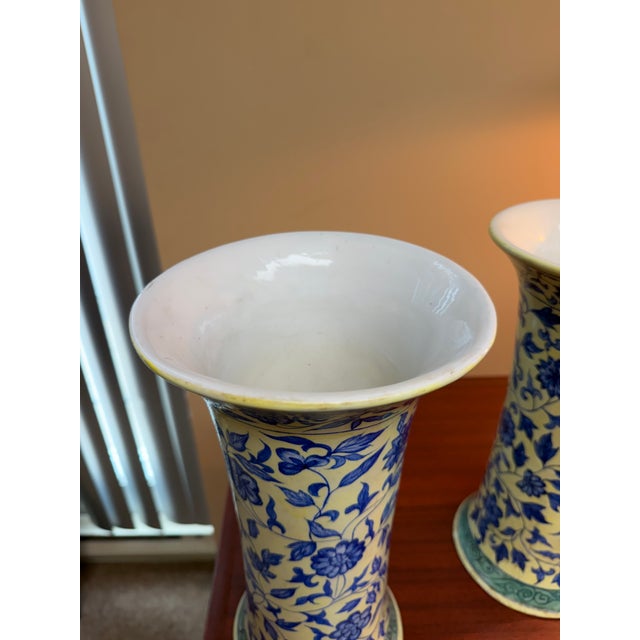 Decorative pair of ceramic vases featuring a tall trumpet-form silhouette with gently flared rims and bases. Each vase is...