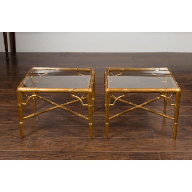 A pair of French vintage gilt faux bamboo drinks tables from the mid-20th century, with glass tops and X-form cross...
