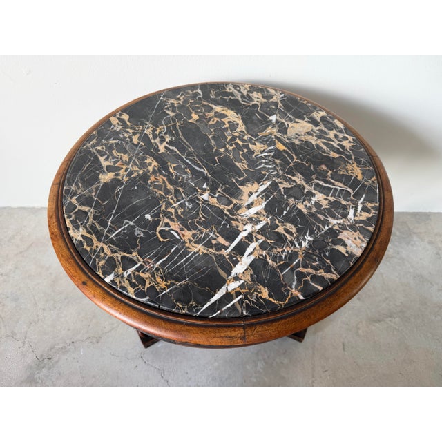 A beautiful 19th-century French accent table showcasing an intricately hand-carved wooden base supported by three...