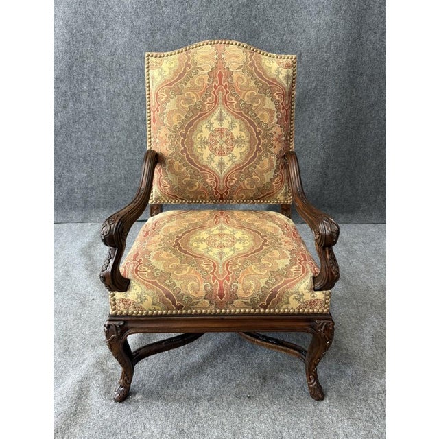 This traditional high-back upholstered arm chair features an elegant, gently arched crest and richly patterned fabric with...
