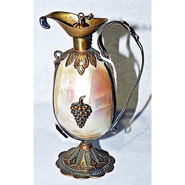 19c France embodied in this mother-of-pearl shell and brass ewer style perfume bottle, sometimes aka: viniagrette, with...