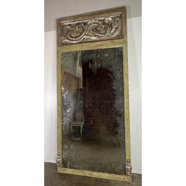 Grand Italian Baroque style trumeau mirror with a painted frame in a gentle shade of green, suggesting an air of...