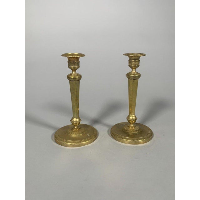 Pair of gilt bronze candlesticks, Empire period, early 19th century. Hexagonal stems resting on a sphere, itself on a...