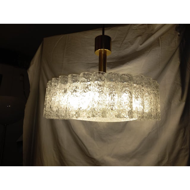 The ceiling lamp is equipped with six E27 sockets. The lamp consists of a metal frame, 32 clear glass tubes, and a large...