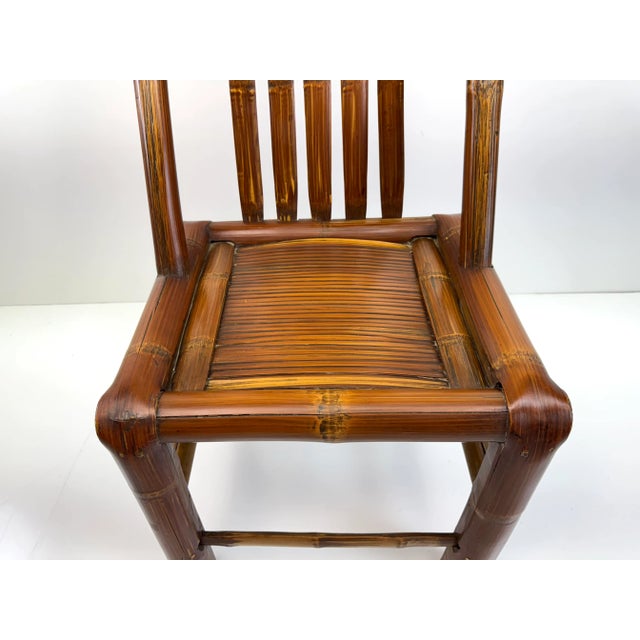 A striking vintage bamboo side chair featuring a tall, sculptural back and hand-crafted joinery that highlights the...