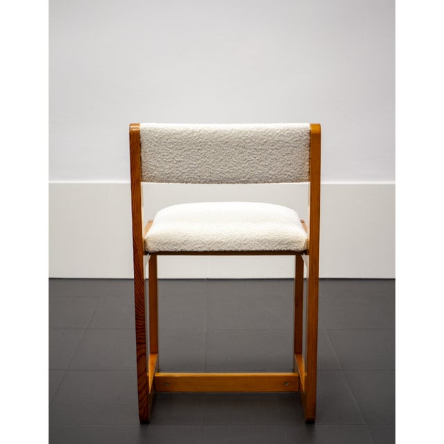Brutalist-style wooden chair upholstered in white bouclé. Shows signs of use and age.