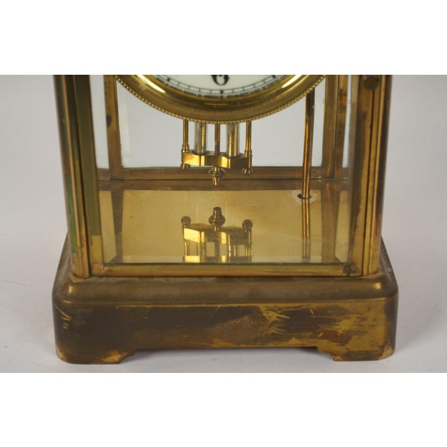 American brass "crystal regulator" style carriage clock with a visible pendulum and open escapement through four beveled...