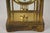 American brass "crystal regulator" style carriage clock with a visible pendulum and open escapement through four beveled...