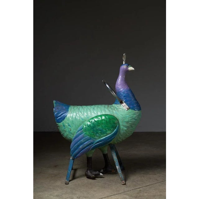 This exquisite antique carousel figure showcases the elegance of a peacock, intricately carved from wood. Mounted on a...