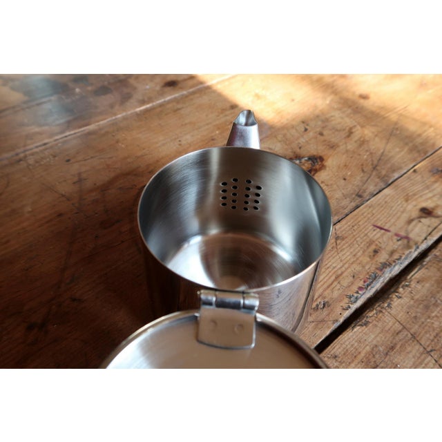 A minimalist stainless steel teapot crafted in 18/10 steel and dated 2001. The design emphasizes functionality and clean...