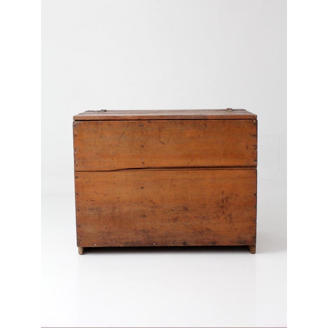 A 19th-century primitive wood chest with a warm, timeworn surface and simple plank construction. The lift top opens to a...