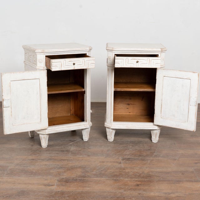 Pair, small Swedish country white painted nightstands or small cabinets standing on tapered feet. Canted sides have simple...