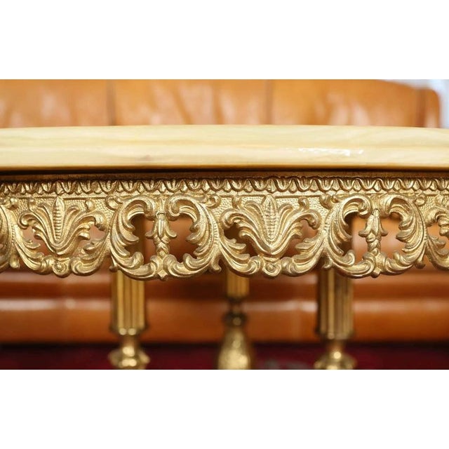 Heavy metal tripod base with floral decoration. Top onyx natural stone top has a cut edge. Richly decorated base....
