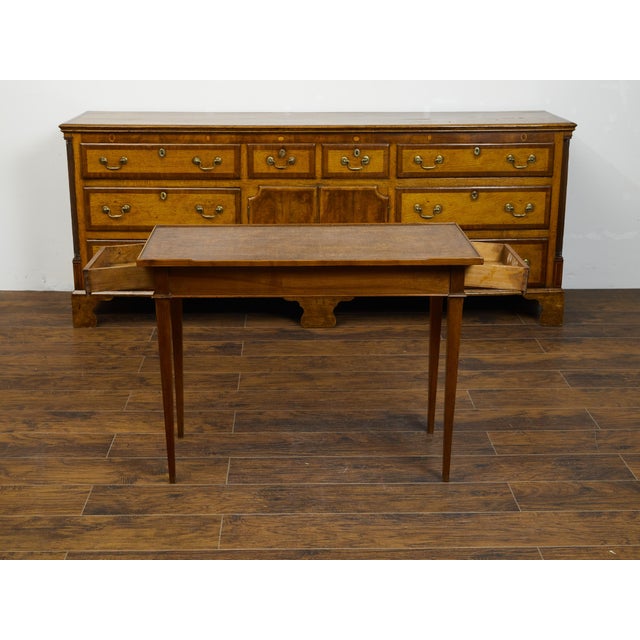 A French Restauration period wooden side table from the early 19th century, with leather top, lateral drawer and tapered...