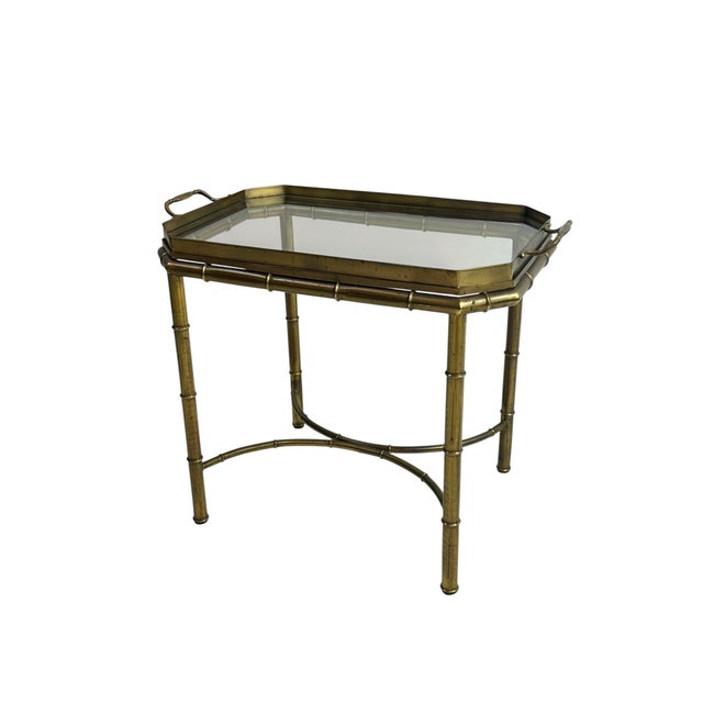 A brass faux bamboo tray table of the Hollywood Regency period, comprising a removable glass-inset tray top with canted...