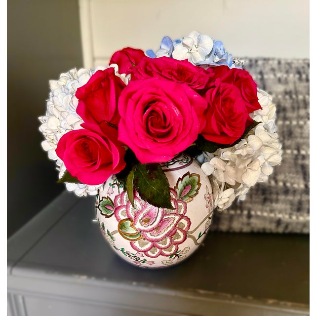 A richly detailed, hand‑painted porcelain vase featuring a lush wraparound floral motif in shades of pink, white, and...