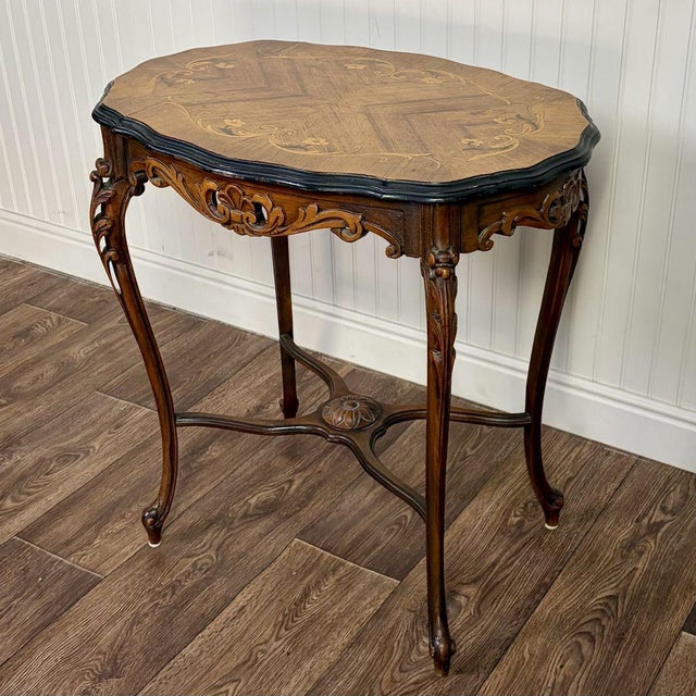 Vintage side or accent table in the Louis XV style with a marquetry inlaid veneer top and a hand-carved base. The...