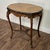 Vintage side or accent table in the Louis XV style with a marquetry inlaid veneer top and a hand-carved base. The...