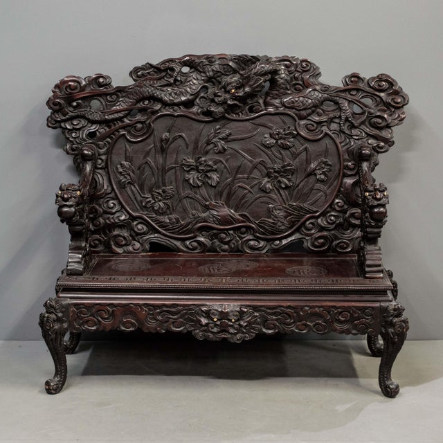 Antique dark red lacquer, Meiji period, Japanese settee featuring a heavily carved dragon and Iris motif. The pierced...