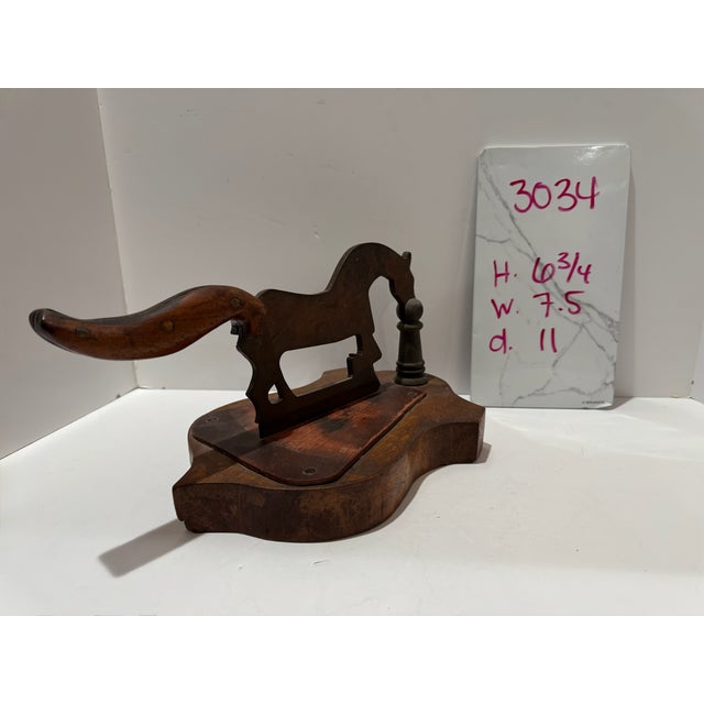 Figural tabletop cutter featuring an iron blade shaped as a horse, with a curved wooden handle extending from the...