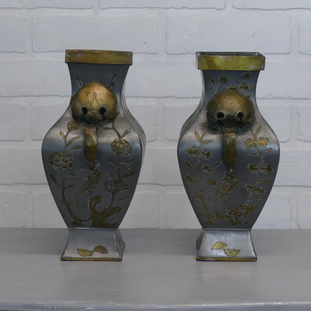 A pair of mid-century Chinese pewter and brass vases accentuated with Asian floral and bird images in etched brass. Age...