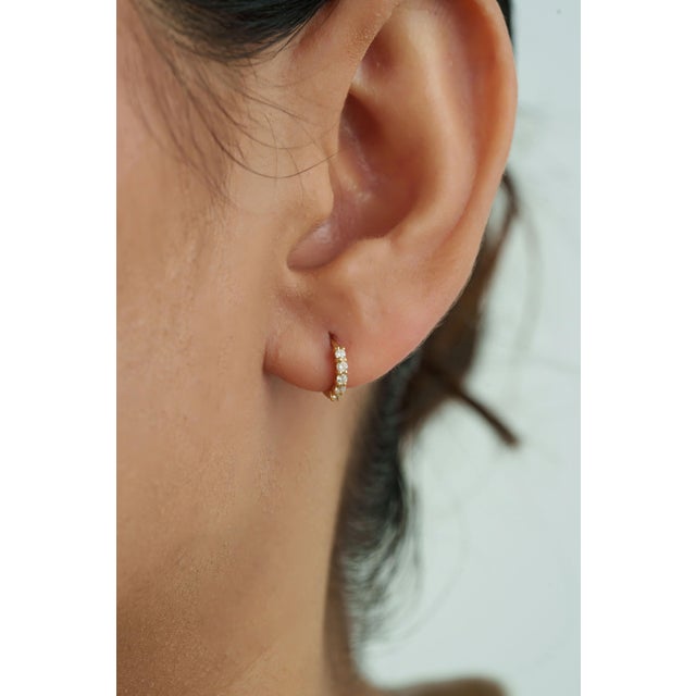These Tiny Diamond Huggie Hoop Earrings feature 0.15 carats of natural diamonds set in 18K Yellow Gold. Each diamond...
