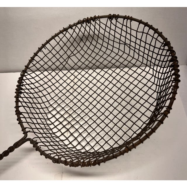 Vintage folk art metal wire scoop with decorative handle.