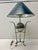 A large, metallic ribbed sphere with a polished finish acts as the visual centerpiece.The lamp is supported by slender...