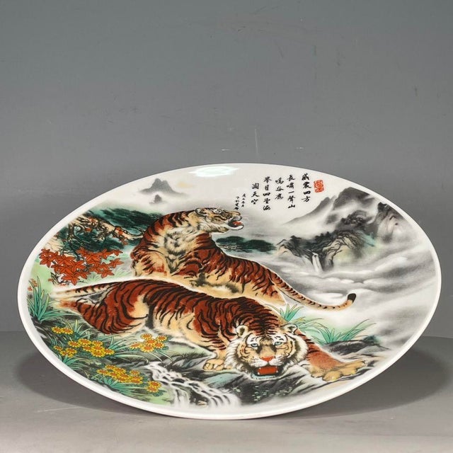 A striking Chinese porcelain charger (plate). The white ground is finely hand-painted with a dynamic scene of two fierce...