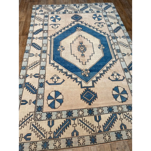 A lovely vintage Oushak rug. This vintage Oushak offers a cream palette with blue and light blue accents.