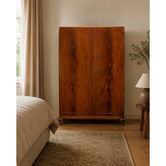 A handsome 1950s double wardrobe with richly figured flame mahogany doors, decorative moulding, ornate drop handles and...
