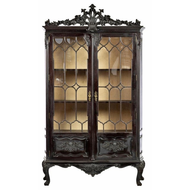 Pair of display cabinets portuguese, early 20th century, in carved chestnut wood with two glazed doors, interior with...